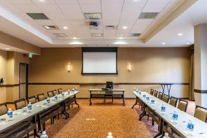 a conference room with tables and chairs and a screen at Hyatt House Denver Lakewood Belmar in Lakewood