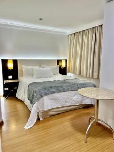 a bedroom with a large bed and a table at Hotel America International Jardins in Sao Paulo