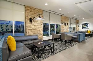 - un salon avec un canapé, des tables et des chaises dans l'établissement Hyatt Place Houston NW Vintage Park, à Houston