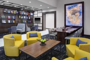 a waiting room with yellow chairs and a table at Hyatt Place Dallas/The Colony in The Colony