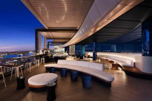 un restaurante en la parte superior de un edificio con mesas y bancos en Hyatt Regency Sydney, en Sídney