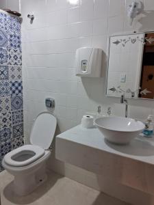 Baño blanco con aseo y lavamanos en Aconchego en Araxá