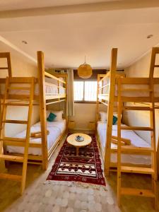 a room with three bunk beds and a table at The Moroccan Surf House in Imsouane