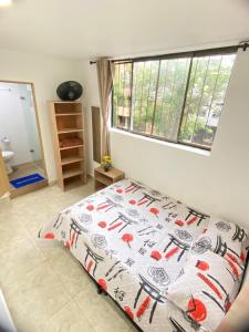 1 dormitorio con cama con edredón y ventana en 23 COMODO APARTAMENTO CON BALCON EN LAURELES ESTADiO, en Medellín