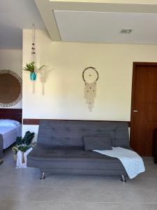 a bedroom with a couch and a clock on the wall at Apartamento na praia Garopaba San Pietro Sc loft 101 in Garopaba