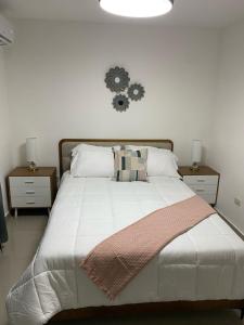 ein Schlafzimmer mit einem weißen Bett mit einer Uhr an der Wand in der Unterkunft Residencial Mediterraneo in Santiago de los Caballeros