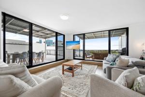 a living room with white furniture and large windows at Beachside 3-Bed with BBQ, Pool, Gym & Tennis Court in Marcoola