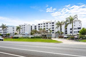 an empty street in front of a white building at Beachside 3-Bed with BBQ, Pool, Gym & Tennis Court in Marcoola