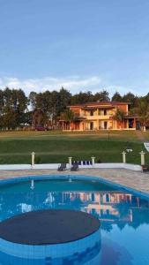 a large swimming pool in front of a house at Chácara tipo resort a maior piscina que vc já viu! in São Pedro