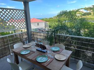 Appartement Saint Martin Friars Bay Sunset Paradise في Friar's Bay: طاولة خشبية مع لوحات واكواب للنبيذ على شرفة