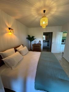 a bedroom with a large white bed and a chandelier at Appartement Saint Martin Friars Bay Sunset Paradise in Friar's Bay