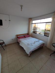um quarto com uma cama e uma grande janela em Soinca Backpacker Hospedaje em Paracas