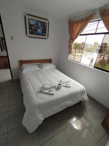 a bedroom with a large white bed with a window at Soinca Backpacker Hospedaje in Paracas