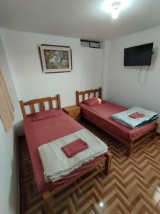 a room with two beds and a television in it at Soinca Backpacker Hospedaje in Paracas