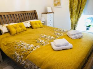 a bedroom with a yellow bed with towels on it at Ty Cwtch in Dolgellau