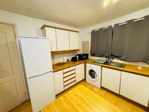 cocina con nevera blanca y lavadora en Home Paradise Manchester- 3 Bedroom House, en Mánchester