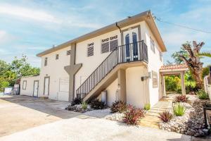 a large white building with a staircase in front at EcoMar Rentals Casa:, Naturaleza, Piscina & Playa in Cabo Rojo