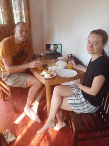 SUPER SUN HOMESTAY في Katugastota: رجل وامرأة يجلسون على طاولة طعام