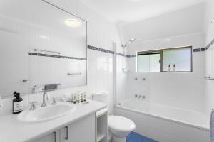 La salle de bains blanche est pourvue d'un lavabo et de toilettes. dans l'établissement Nautilus Noosa Holiday Resort, à Noosaville