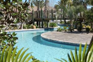 a swimming pool with a bridge and palm trees at Lovely Condos 18 Minutes away from Disney! in Kissimmee
