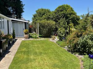 a garden with green grass and trees and a house at Orange Tree Cottage - garden hideaway in Whanganui