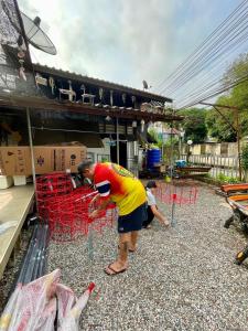 a man bending over in front of red chairs at Pano Solar Guest House (พาโน โซล่า เกสเฮ้าส์ ) in Trat