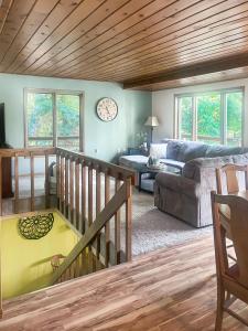 a living room with a couch and a clock on the wall at 2br Lakeside Haven Relax On Long Lake in Gleason