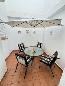 - une table avec des chaises et un parasol dans la chambre dans l'établissement Sol y playas, à Conil de la Frontera