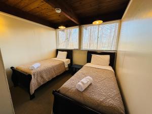 two beds in a small room with two windows at Excelsior at the Manor House in Clemmons