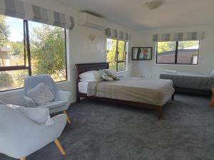 a bedroom with a bed and a chair and windows at Harakeke Homestay in Hastings