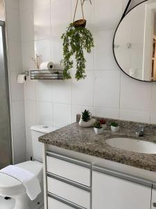 a bathroom with a sink and a toilet and a mirror at Anfitrião Guiah! - Desperte os sentidos a beira-mar e ao lado do Centro de Convenções in Salvador