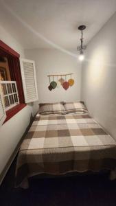 a bedroom with a bed with a checkered blanket at CASA DOS SINOS in São João del Rei