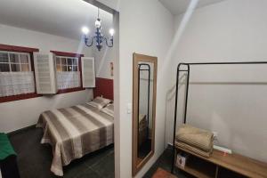 a small bedroom with a bed and a mirror at CASA DOS SINOS in São João del Rei