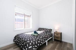a bedroom with a black and white bed and a window at Mt Baker Home:10km to Hahndorf in Mount Barker