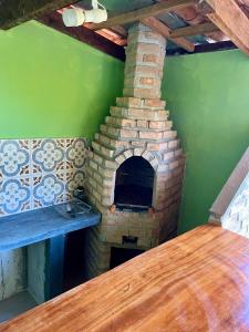 een bakstenen oven in een groene kamer met een houten tafel bij Barbosa acomodações. Lencois-BA in Lençóis