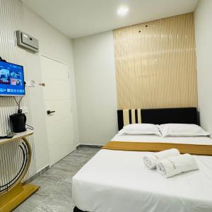 1 dormitorio con 1 cama con sábanas blancas y TV en Rayyaz Inn en Kuala Terengganu