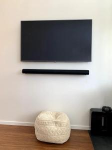 a flat screen tv hanging on a wall with a stool at Tiny House - Big Luxury in Wanaka