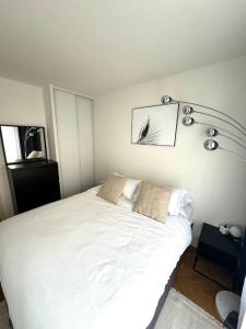 - une chambre avec un lit blanc et 2 oreillers dans l'établissement Charmant appartement aux portes de Paris, à Asnières-sur-Seine