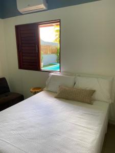 uma cama branca num quarto com uma janela em CASA SONHO VERDE 5 QUARTOs 3 suítes CONDOMÍNIO BEIRA-MAR em Paripueira