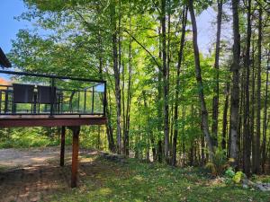 a deck with a chair in the middle of the woods at Chalet in the Laurentian Mountains in Sainte-Agathe-des-Monts
