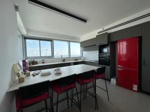 a kitchen with a red refrigerator and a counter with stools at SkyHostel_32Floor in Netanya