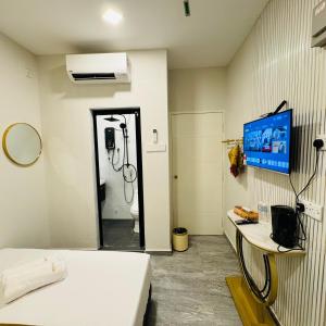 um quarto com uma casa de banho com um chuveiro e uma televisão em Rayyaz Inn em Kuala Terengganu