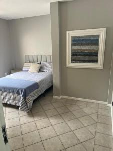 ein Schlafzimmer mit einem Bett und einem Gemälde an der Wand in der Unterkunft Apartamento na melhor localização da meia praia em itapema com garagem para camioneta suv in Itapema