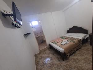 a small bedroom with a bed and a television at Hotel Las Dalias in Guatapé