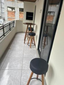 d'un balcon avec une table, deux tabourets et une télévision. dans l'établissement Apartamento na melhor localização da meia praia Itapema, à Itapema