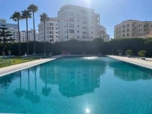 a large blue swimming pool with buildings in the background at Ocean Breeze Malabata Appartement in Tangier