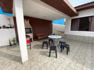 un patio con taburetes, mesa y sofá en Beach House, en Mongaguá