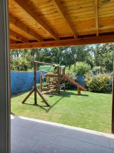 un patio con parque infantil y techo de madera en Espejos de monte en San Miguel del Monte