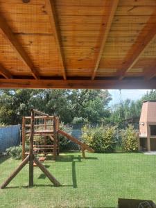 un parque infantil de madera en un patio con techo en Espejos de monte en San Miguel del Monte