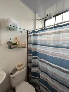 y baño con aseo y cortina de ducha. en LakeLifeCR Tu casa frente al Lago Arenal, en Tilarán